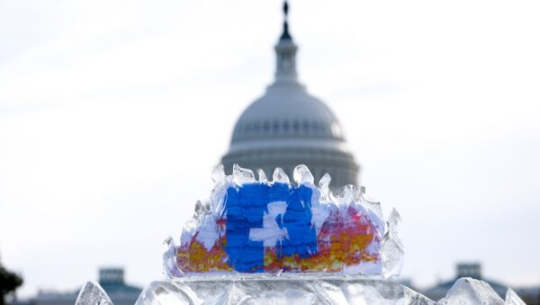 an iceblock with a facebook symbol inside it. The iceblock is infront of a white building