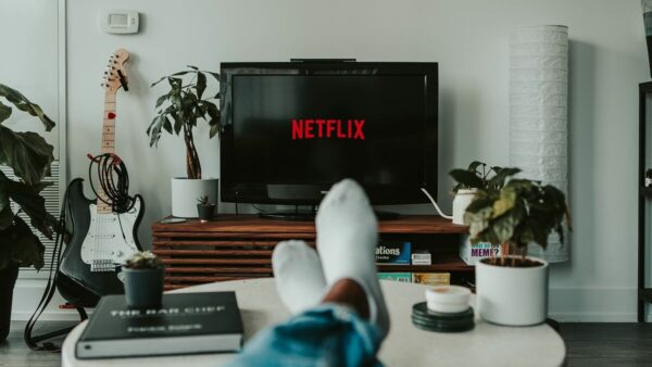 a living room. A person has their feet on acoffee table. the TV screen has red letters saying Netflix