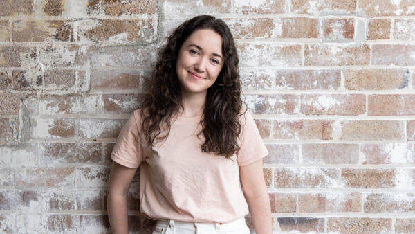 Young woman (scientist-in-residence at Blackbird) with curly hair smiling at camera