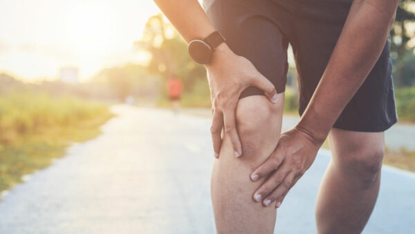 man running and holding knee with osteoarthritis pain