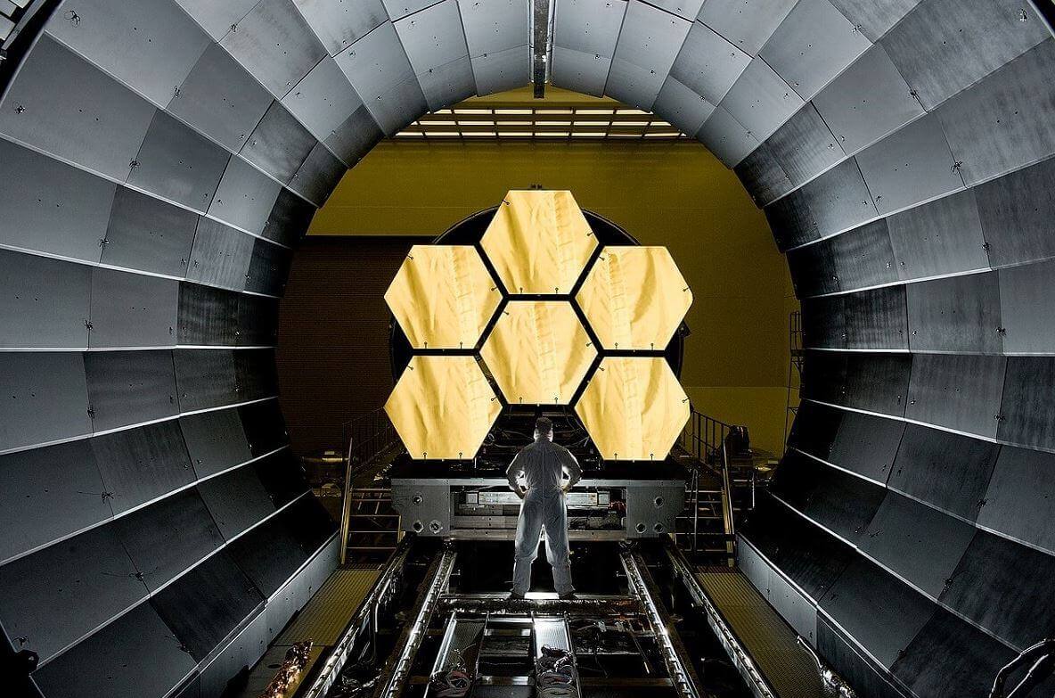 Person stands in front of 6.5 metre hexagonal golden mirror