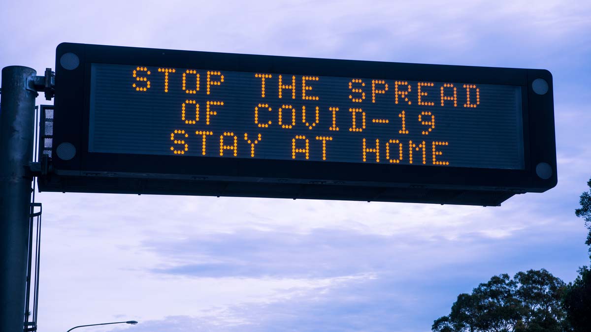 led traffic sign saying stop the spread of covid-19 stay at home