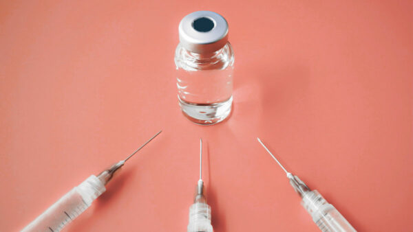 vaccine effectiveness concept: 3 syringes pointing to vial; orange background