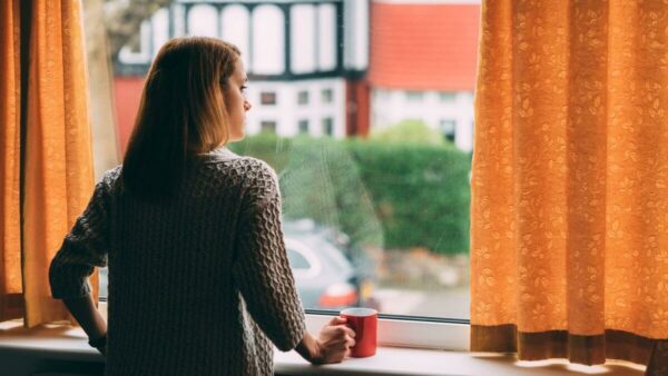 woman alone in house looking out window