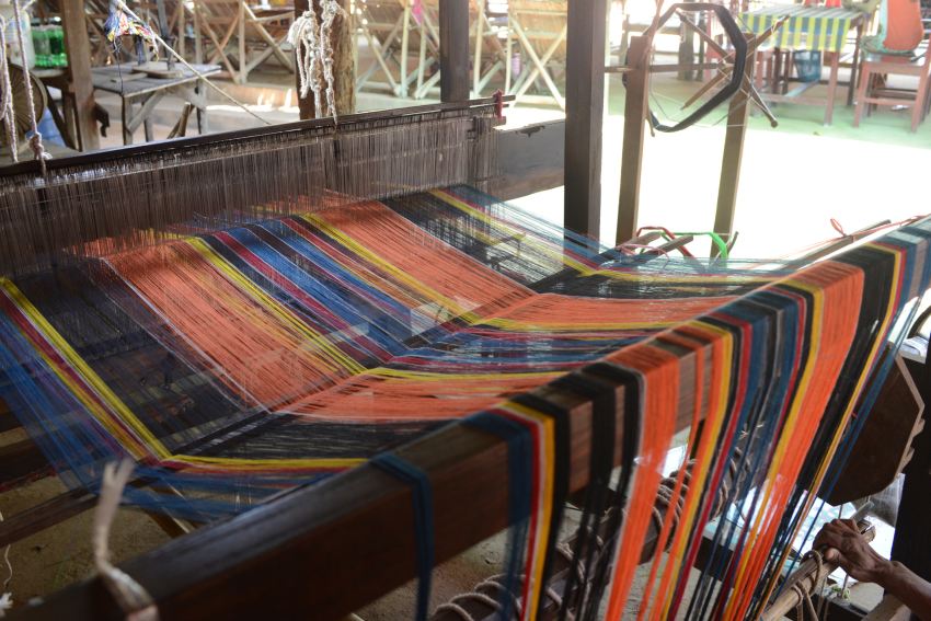 brightly coloured threads suspended over a yarning machine