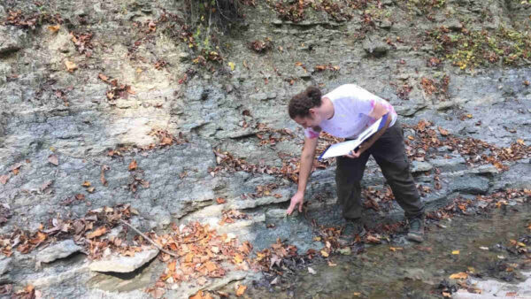 geologist-ian-forsythe-looking-at-stratified-rocks-on-creek-bed