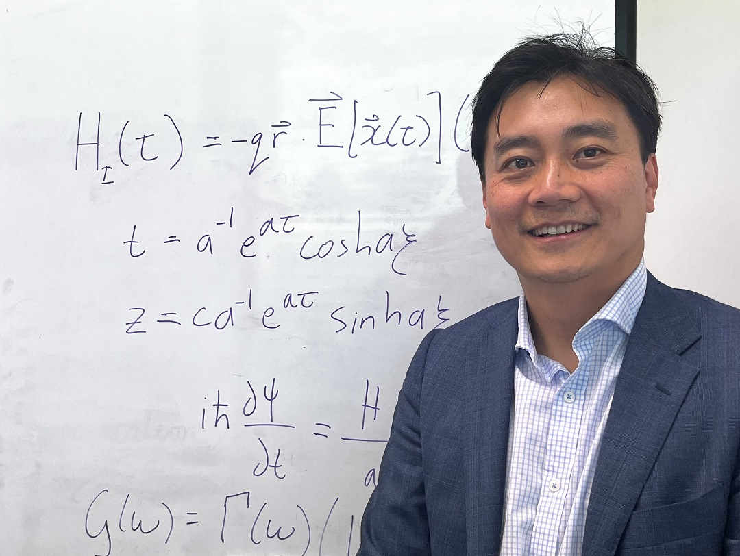 james-quach-stands-in-front-of-whiteboard-with-hamiltonian-equations-schrodinger