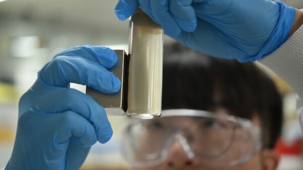 researcher holding a magnet up to a vial of pfas contaminated water