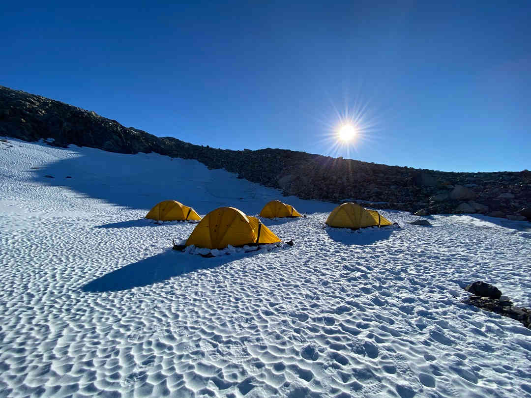 yellow-tents-in-antarctica-on-ice-field-under-low-sun-blue-sky