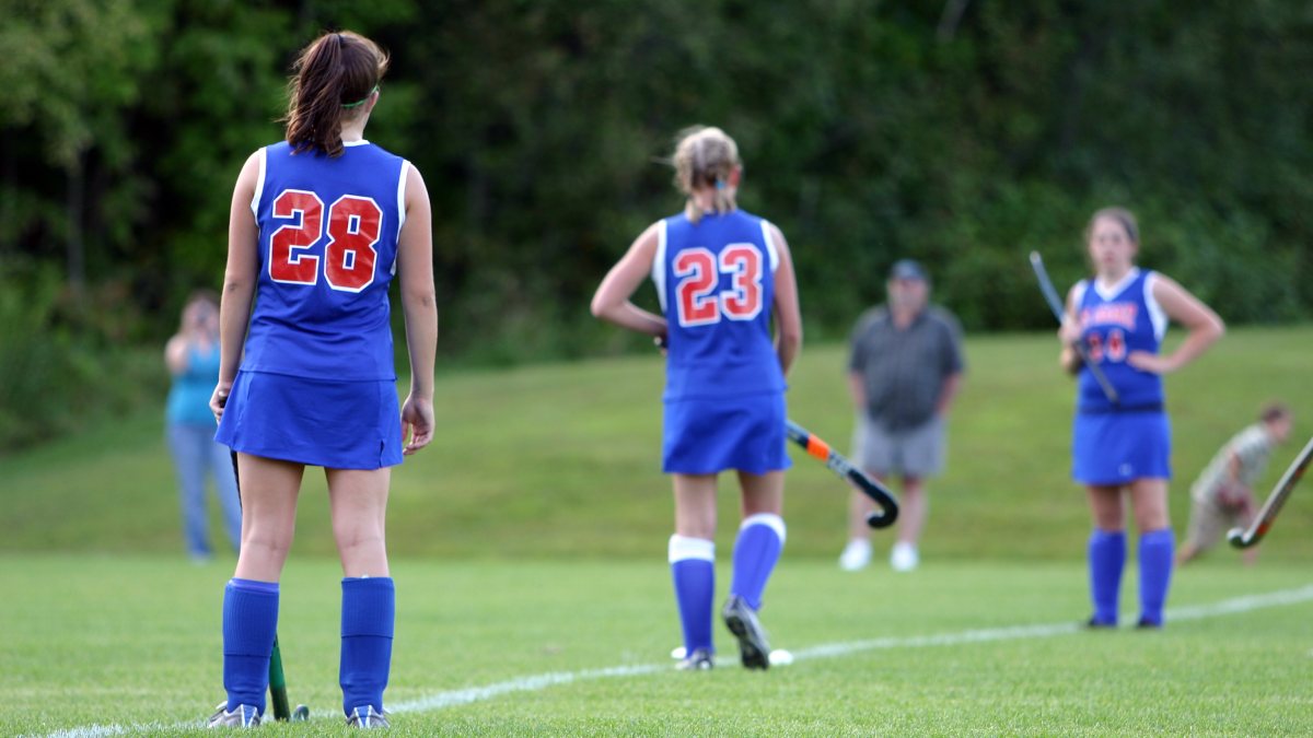 girls playing hockey in sports uniform which includes skorts